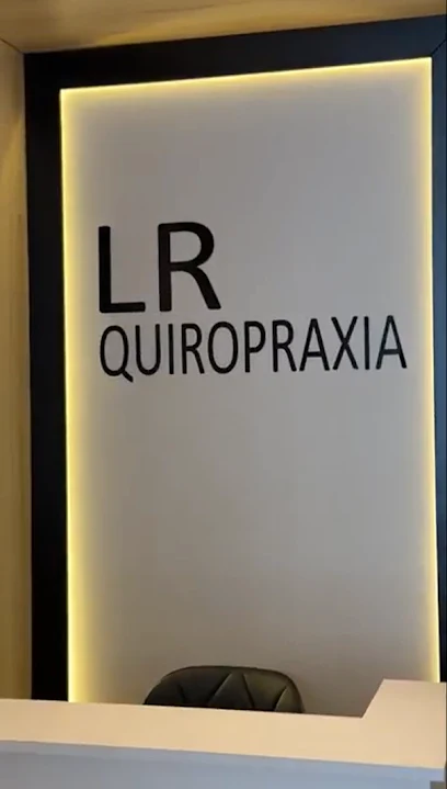 Recepção real da LR Quiropraxia com iluminação acolhedora e identificação da clínica